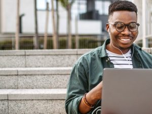 murdoch-university-dubai-man-works-on-laptop-outdoors-on-stairs-1440x548-1.jpg